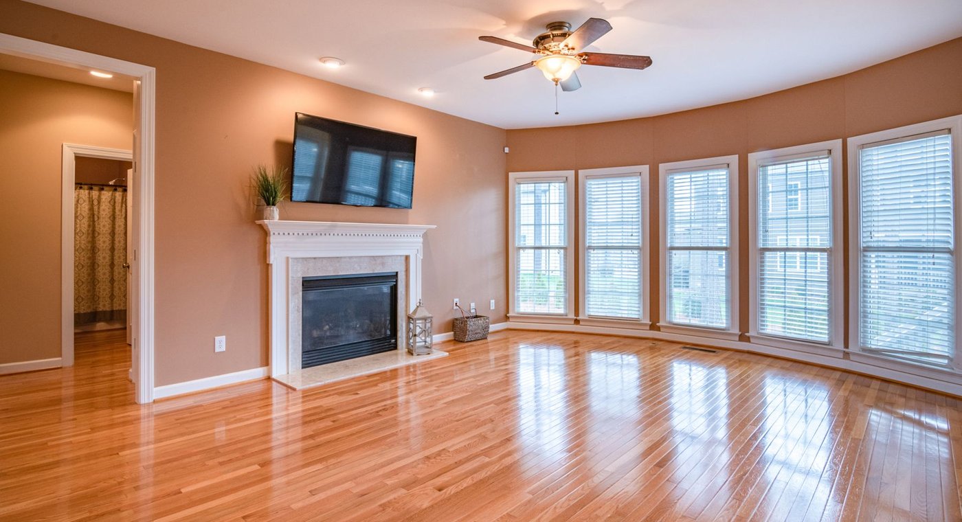 Finished living room with hardwood floors, a ceiling fan and a wall-mounted TV