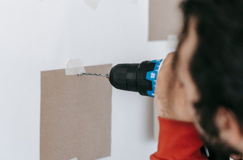Drilling into a wall through a paper template to hang items