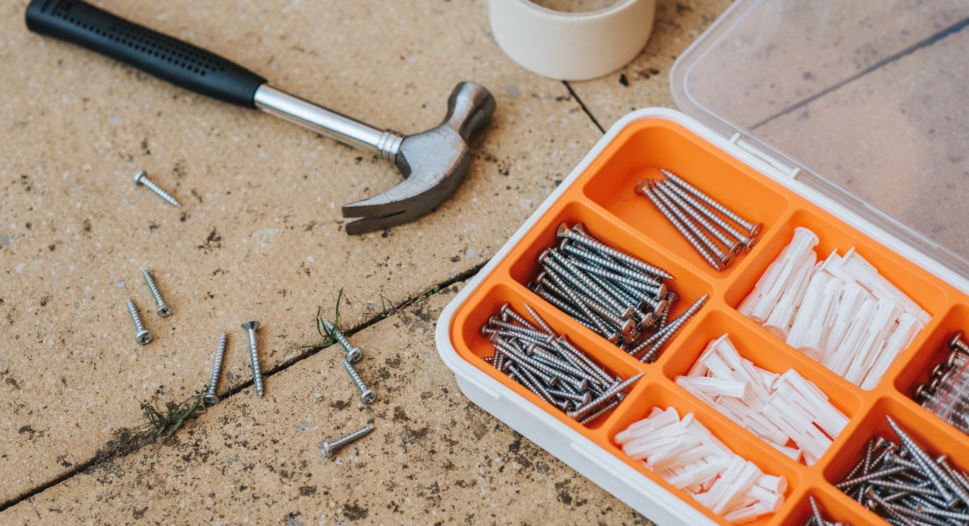 A claw hammer, a roll of tape and an open case of screws and wall anchors